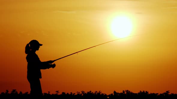 Silhouette of Female Fisherman Throws Fishing Tackle