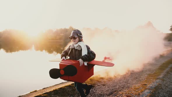 Happy Little Pilot Girl Playing, Running Along Sunset Lake in Fun Cardboard Plane Costume with Color