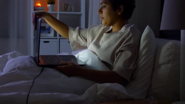 Woman with Laptop in Bed at Home at Night