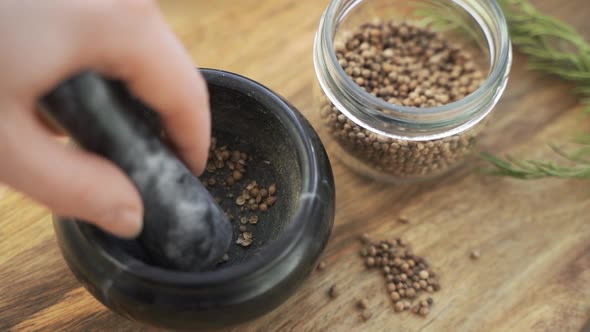 Woman's Hand Mixes and Crushes Coriander Seeds By Granite Mortar with Pestle in Slow Motion