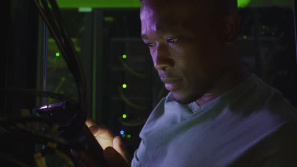 African american male computer technician using smartphone working in business server room