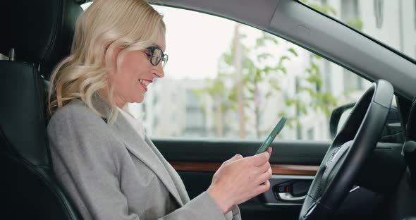 Woman Chatting or Browse Videos or Photos or Social Networks on Smartphone While Sitting in Car.