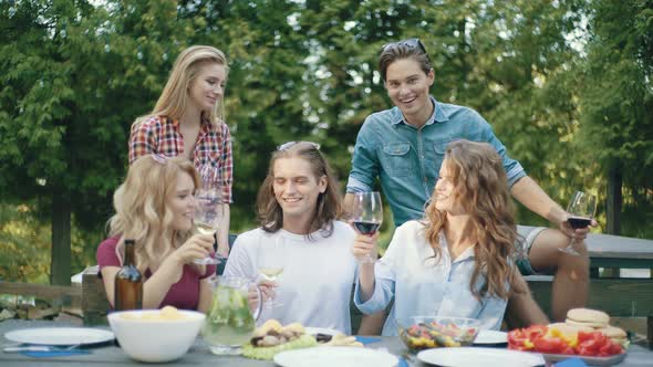 People Cheering With Drinks At Outdoor Dinner Party