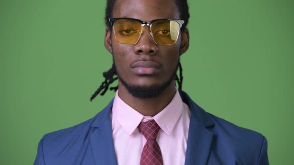 Young Handsome African Businessman with Dreadlocks Against Green Background