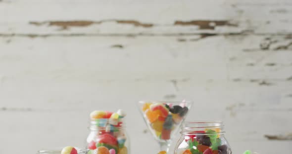 Video of colourful various sweets in glass vessels on wooden table