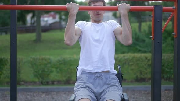 Motivated Focused Man in Wheelchair Doing Pull Ups in Slow Motion Outdoors