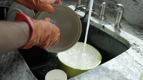 View of Hands in Orange Gloves Wash Dishes in the Kitchen