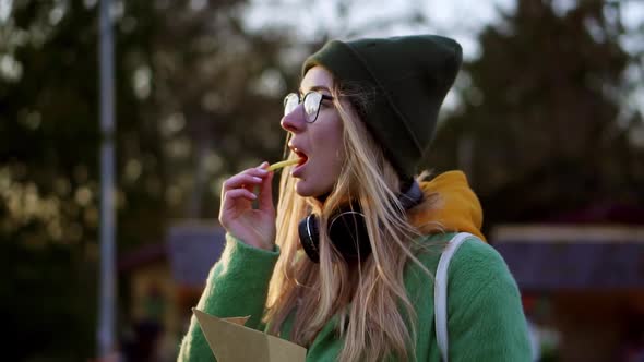 Blonde Girl Eating French Fries Outdoors on Winter Street Dip in Ketchup