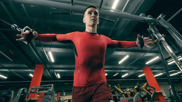 A Man Is Using a Fitness Machine for Arms During His Workout