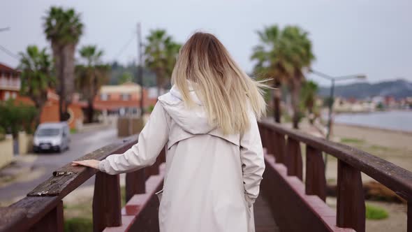 Blonde Woman Walking on Small Wooden Bridge in a Small City