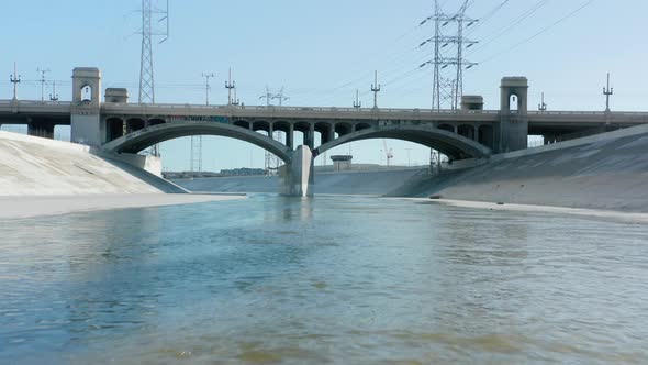 Drone Flying Low Above Scenic Blue Los Angeles River Water Under Concrete Bridge