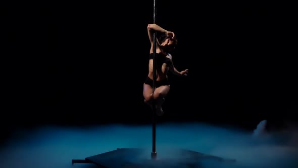 Striptease Dancer in Blue Smoke on a Pole. Black Smoke Background. Slow Motion