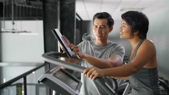 Asian Sportsman Helping Woman in Gym