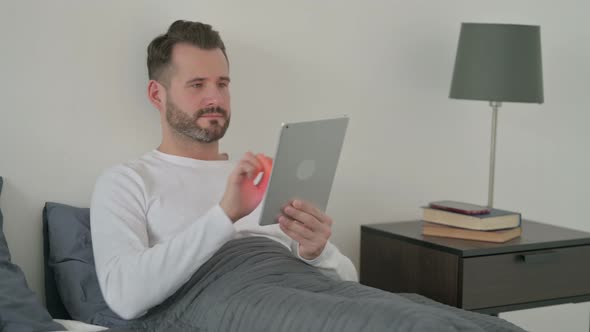 Man Using Tablet in Bed