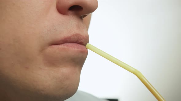 Closeup Face of Young Man Drinking Through Plastic Cocktail Tube Light Background