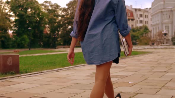 Back View Woman Walks To Class Holding Book