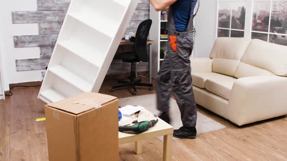 Fit Male Worker in Coverall Picks Up Furniture