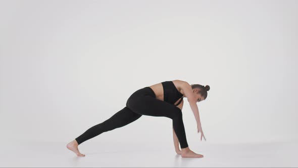 Young Flexible Practicing Trikonasana and Downward Dog Poses Stretching Her Back Over White Studio