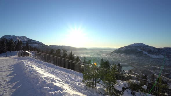 Walking motion on Snow covered top mountain with beautiful Bergen city at sunrise