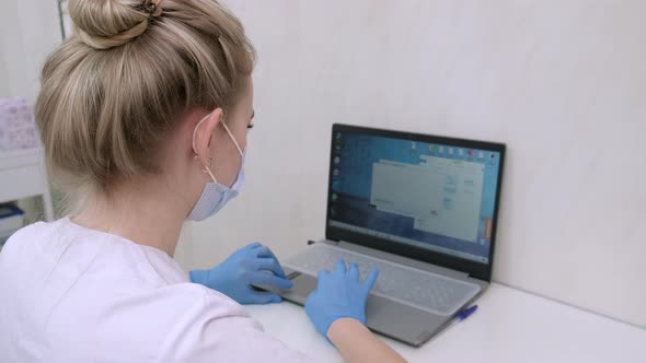 Dentist Assistant or Nurse Working on Laptop Computer in Dental Clinic