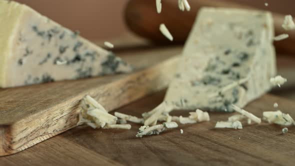 Super Slow Motion Shot of Grated Blue Cheese Falling on Wooden Board at 1000 Fps.