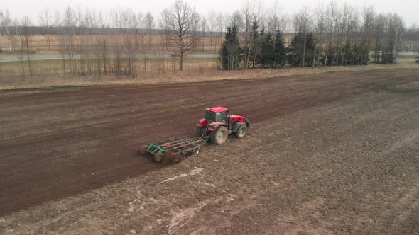 Aerial Tractor Cultivates Land on Farmland Near the Highway