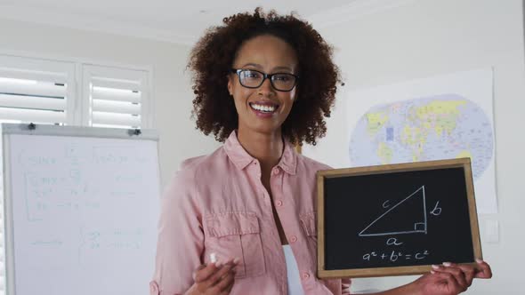 Mixed race female teacher standing at a whiteboard giving an online lesson to camera