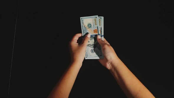 Woman Hands Take and Show a Fan of Dollar Bills on the Black Background