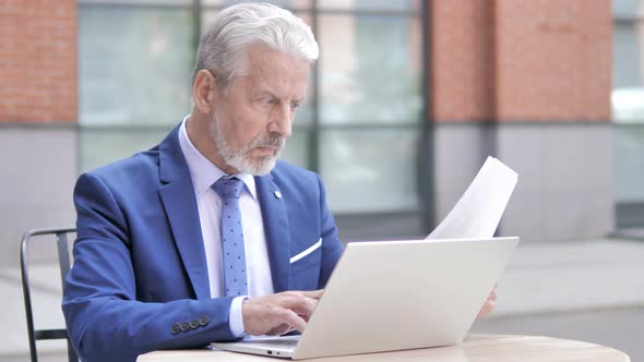 Old Businessman Working on Documents and Laptop Outdoor