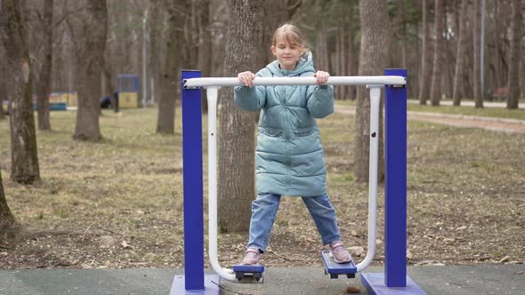 a Little Girl is Engaged in Mechanical Sports Simulators in the Park