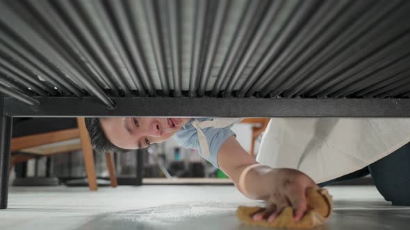 Asian father using fabric wiping dust on furniture, cleaning floor under the sofa for family at home