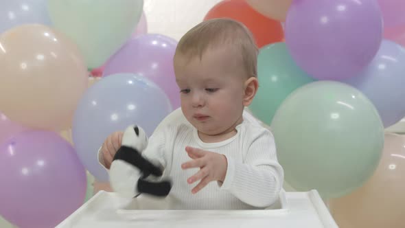 Happy Little Boy Holding Gift Toy at Birthday Party in Slow Motion One Year Old Kid Against Colorful
