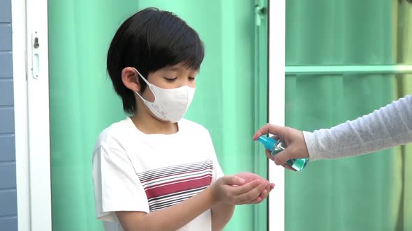 Asian Mother Spraying Sanitizer On Son Hands