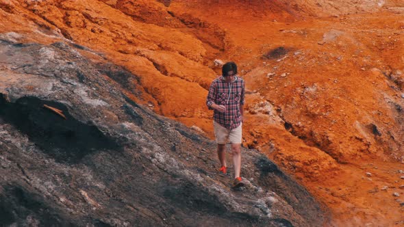 A Young Man Traveler Walks on Orange Clay Rocks