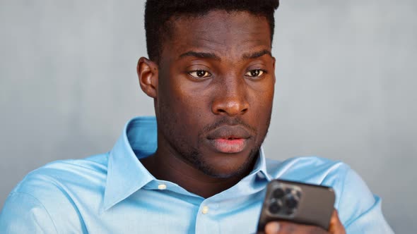 Young serious guy sending a message using a smartphone