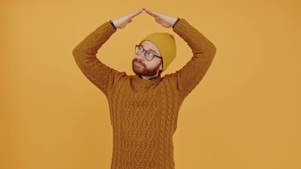 Pensive Reasonable Millennial Man Holding His Hands Over His Beanie and Looking Around By Turning