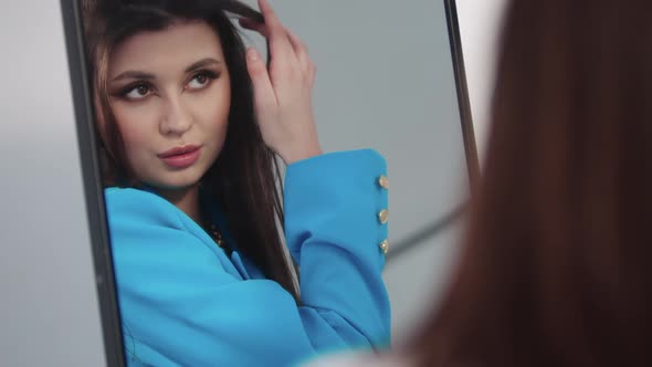 A Young Beautiful Woman in a Blue Blazer Flaunts Herself in Front of a Mirror