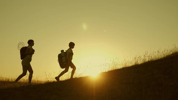 Children and Mom with Backpacks Travel Climb Mountain in the Sun. Mom and Daughters Go Camping