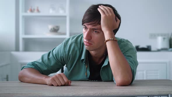 Portrait of Worried and Stressed Young Man Sitting at Table at Home