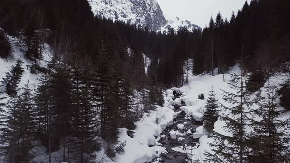 Aerial drone shot of a small valley with a trail and a creek in the alps, Kleinwalsertal, Austria, w