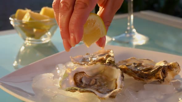 Hand Squeezes Juice From Lemon Into Open Oysters