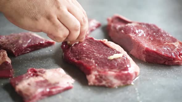 Chef greases raw barbecue meat with garlic