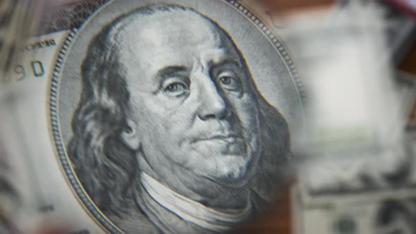 One Hundred Dollars Inspecting Under Magnifying Glass on Money Background