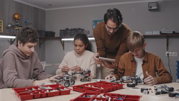 Young Man Helping Kids With Robots