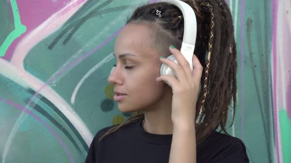 Young Modern Woman Listening to Music with Headphones Outdoors