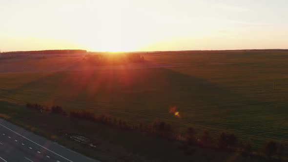 Drone Shooting of a Beautiful Summer Landscape with Forest and Meadows at Sunset and Busy Traffic on