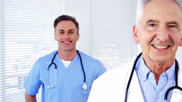 Portrait of male doctors and coworker standing with arms crossed