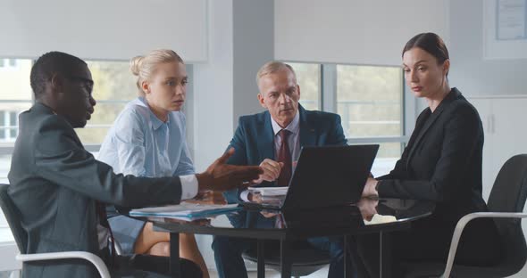 Diverse Business Team Working in Modern Workplace Office with Laptop and Documents on Table