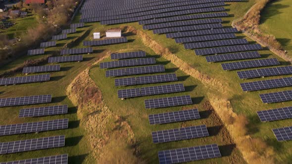 A large photovoltaic power station in front of a small village in Europe. Aerial fly over reveal