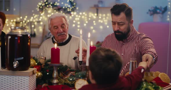 Man Praying While Sharing Christmas Dinner with Family